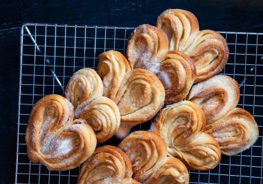 Homemade sugar buns on a cooling rack. Palmiers, elephant ear, puff pastry cookie clipart