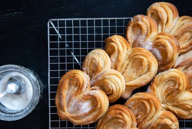 Ev yapımı şekerli çörekler serpmek için serinletici rafta. Palmiye, fil kulağı, puf böreği.