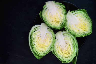 Siyah arka planda siyah bir tabakta lahana ikiye bölünmüş. Kopyalama alanı olan üst görünüm