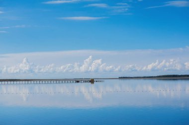 Mavi gökyüzü sakin gölde yansıyan. Beyaz bulutlar bir gölde yansıyan. Bulutlar düşük göl üzerinde dur. Açık mavi gökyüzü