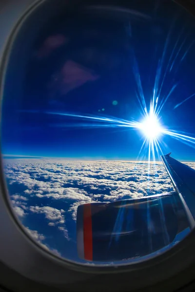 飛行機の窓からタービン、青の雲、太陽の明るい光を見ることができます。 — ストック写真