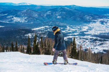 Sheregesh dağlarında başarılı bir snowboard sporcusu. Gökyüzünün arka planında beyaz bir snowboardcu. Beyaz kaykaycı, şık biri. Sheregesh 'te kış manzarası.