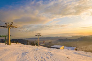 Sheregesh 'te kış manzarası. Turistler, kayakçılar ve snowboardcular için. İnsanları dağlara taşımak için. Mavi dağların arkasındaki teleferik. Dağlarda füniküler