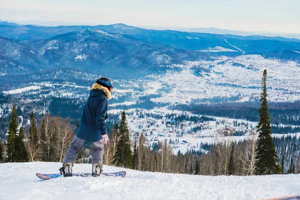 Joven exitoso haciendo snowboard en las montañas Sheregesh. snowboarder caucásico sobre un fondo del cielo. Elegante snowboarder caucásico. Paisaje invernal en Sheregesh. —  Fotos de Stock