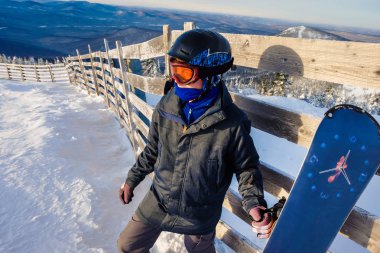 Sheregesh dağlarında başarılı bir snowboard sporcusu. Snowboardcu dağın tepesinde dinleniyor. Mavi gökyüzünün arka planında beyaz bir snowboardcu. Beyaz kaykaycı, şık biri. kayak merkezi