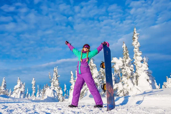 Jovencita exitosa haciendo snowboard en las montañas Sheregesh. Snowboarder descansando. Elegante snowboarder caucásico. Snowboarder sonriendo a la cámara en la cima de la montaña sobre un fondo del cielo. —  Fotos de Stock