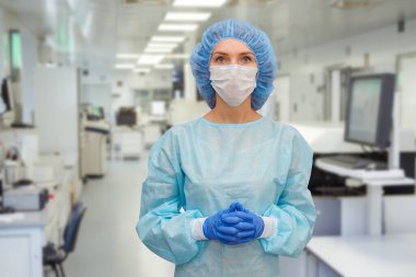 Önlüklü doktor portresi. Korunaklı şapkalı ve yüz maskeli bir kadın doktor. Koronavirüse karşı güvenlik önlemleri almış..