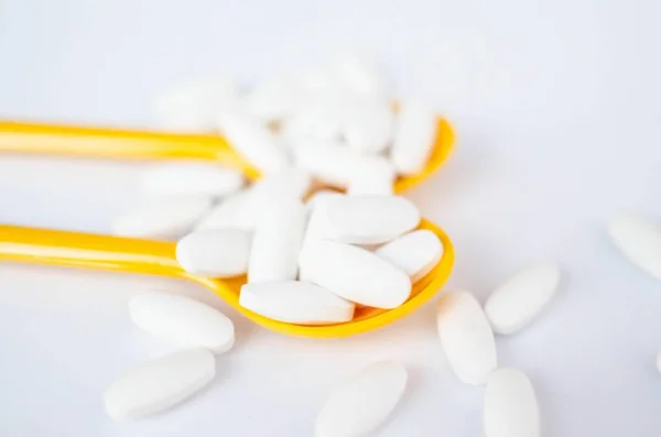 Bílé pilulky léku v žlutá lžička — Stock fotografie