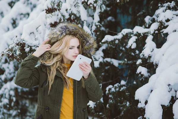 Girl model posing in winter park video calls tablet