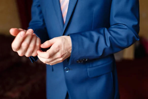 Seorang pria dalam setelan biru meluruskan lengan bajunya. Elegan pengusaha di sebuah hotel mahal, pergi ke pertemuan — Stok Foto