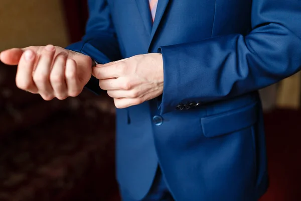 A man in a blue suit straightens his sleeves. Elegant businessman in an expensive hotel, going to a meeting — Stock Photo, Image