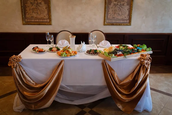 Una mesa festiva decorada para novios, decorada con tela y flores — Foto de Stock