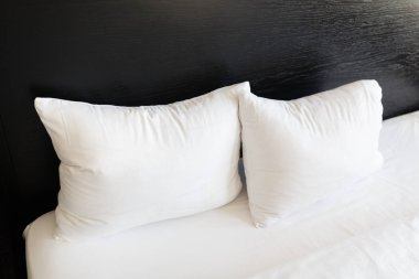 Beyaz yastıklar ile siyah bir arka yatakların üzerinde. Yatak temiz beyaz yastık ve yatak örtüsü odadaki ile yaptı. Yakın çekim.