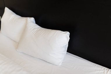 Beyaz yastıklar ile siyah bir arka yatakların üzerinde. Yatak temiz beyaz yastık ve yatak örtüsü odadaki ile yaptı. Yakın çekim.