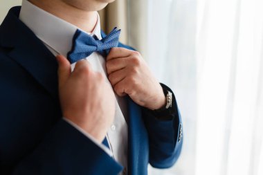 Pahalı bir takım elbise içinde bir adam kravatını düzeltiyor. Zarif işadamı Mavi takım elbise, bir toplantıya gidiyor kravatını pahalı bir otelin düzeltiyor