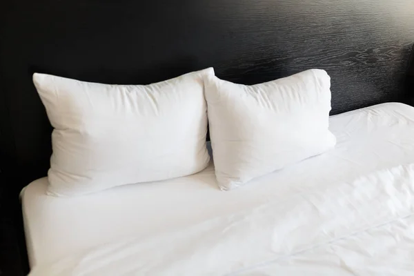 White pillows on the beds made with a black back. Bed made up with clean white pillows and bed sheets in room. Close-up. — Stock Photo, Image