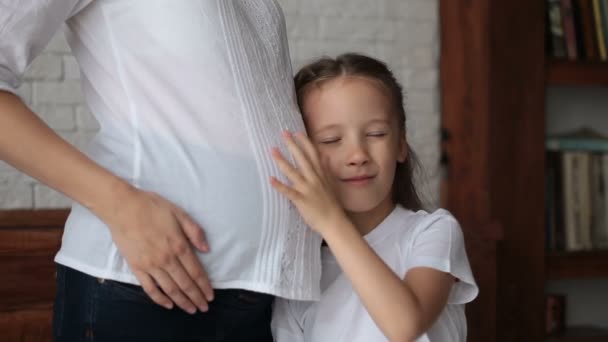 Schattig klein meisje in de buurt van de buik van haar zwangere moeder — Stockvideo