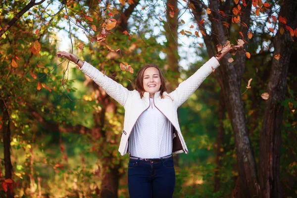 Jeune belle adolescente jette des feuilles d'automne colorées dans le parc — Photo