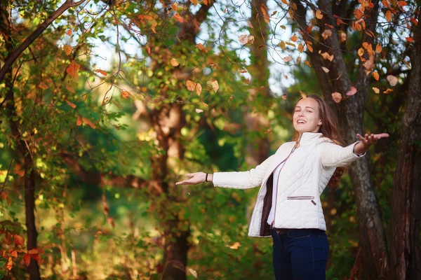 Young beautiful teenager girl tosses colorful autumn leaves in park — 图库照片