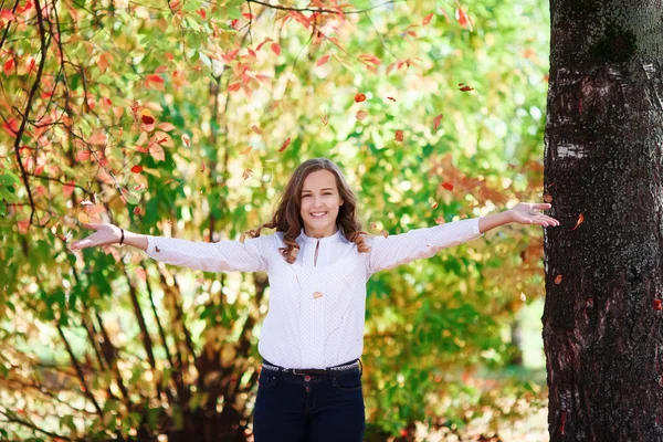 Jeune belle adolescente jette des feuilles d'automne colorées dans le parc — Photo