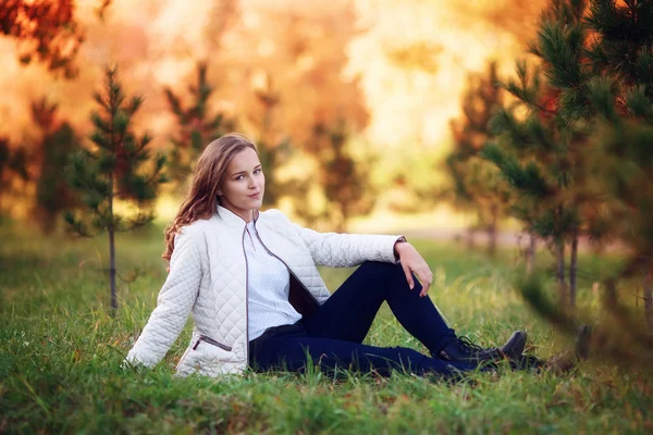 Young beautiful woman. Beauty teenager girl sitting in autumn park — Zdjęcie stockowe