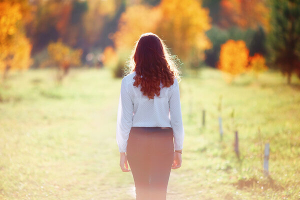 Young beautiful woman. Beauty girl with long hair, back view. Autumn park