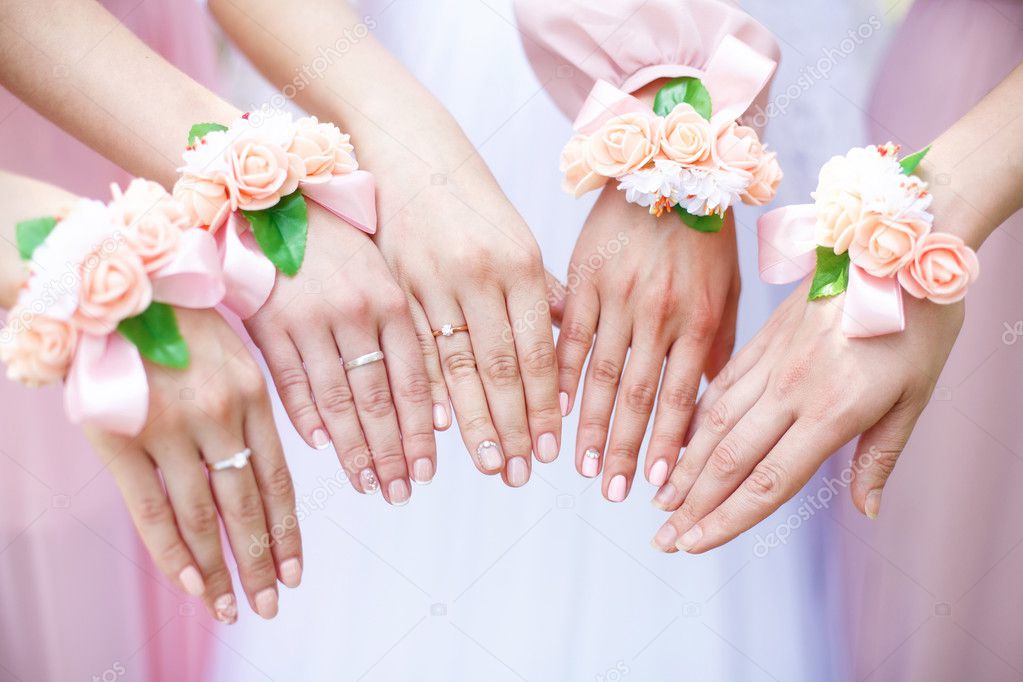 Bride and bridesmaids with flower bracelets on hands. Closeup