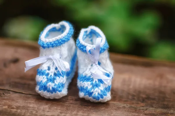 Голубые вязаные детские ботинки ручной работы на деревянном фоне, подтяжка — стоковое фото