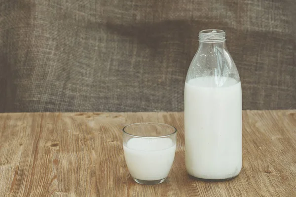 Botella de leche fresca y un vaso sobre mesa de madera —  Fotos de Stock