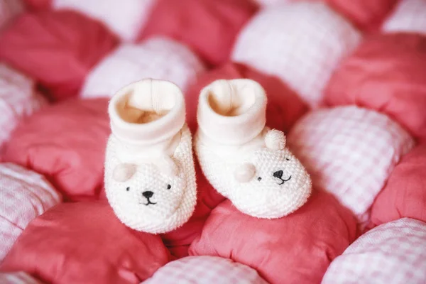 Bonito botas de bebê branco em cobertor vermelho. Conceito de gravidez — Fotografia de Stock