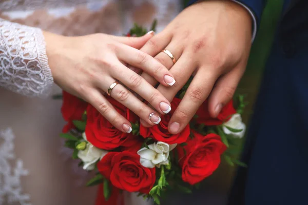 Händerna på bruden och brudgummen på bröllop bukett. Äktenskap koncept — Stockfoto