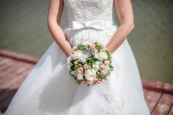 Sposa in abito bianco tenendo mazzo in mano — Foto Stock