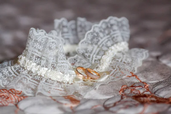 Decorated wedding garter with two golden rings. Marriage concept — Stock Photo, Image