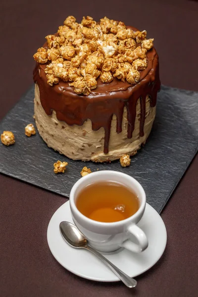 Шоколадний торт з карамеллю та попкорном, чашка чаю, крупним планом — стокове фото