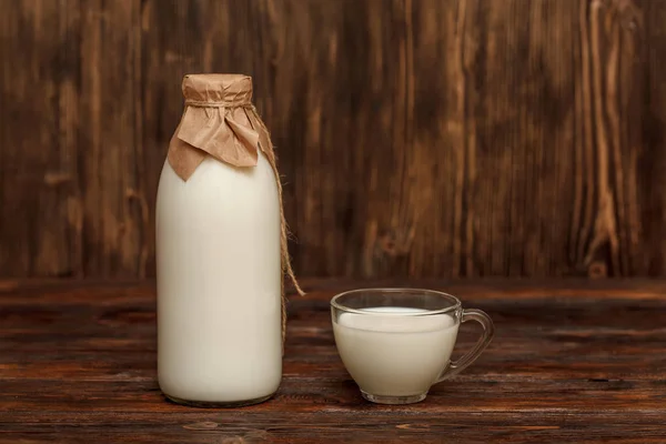 Fles melk en cup op rustieke houten tafel — Stockfoto