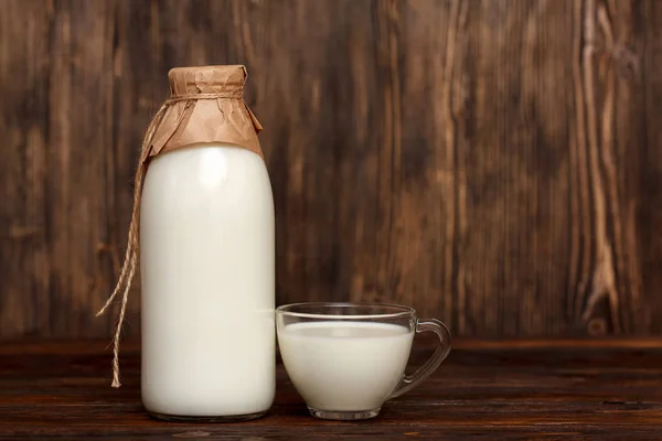 Botella de leche y taza sobre mesa rústica de madera —  Fotos de Stock