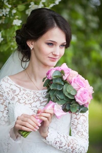 Giovane bella donna, sposa con bouquet da sposa in giardino fiorito — Foto Stock