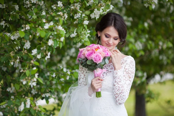 Giovane bella donna, sposa con bouquet da sposa in giardino fiorito — Foto Stock