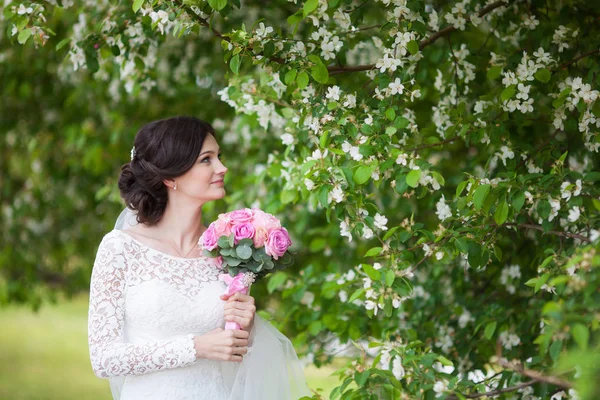 Giovane bella donna, sposa con bouquet da sposa in giardino fiorito — Foto Stock