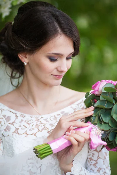 Giovane bella donna, sposa con bouquet da sposa in giardino fiorito — Foto Stock