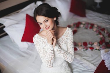 Genç kadın, yatağın üstüne oturan otel içinde gelin