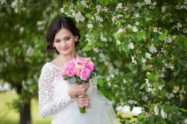 Giovane bella donna, sposa con bouquet da sposa in giardino fiorito — Foto Stock
