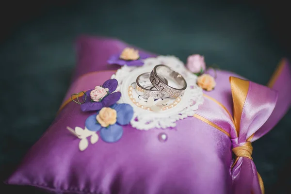 Anéis de casamento em travesseiro roxo, foco seletivo — Fotografia de Stock