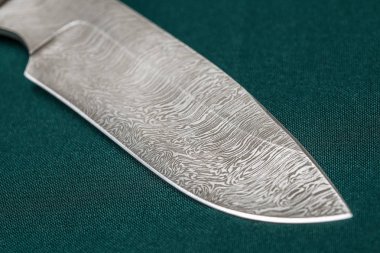 Hunting damascus steel knife handmade on a green fabric clipart