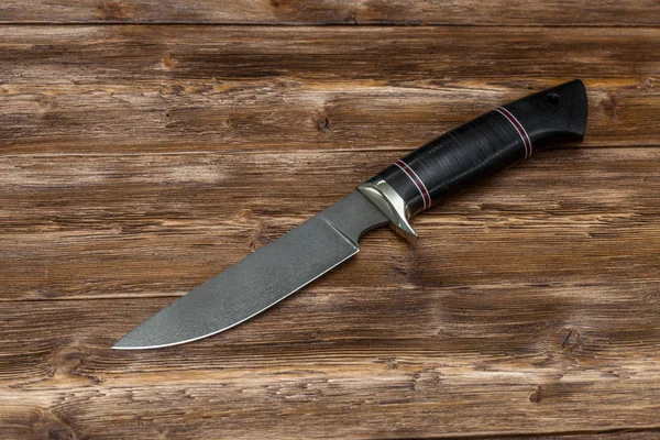 Caça faca de aço feito à mão em um fundo de madeira, close-up — Fotografia de Stock