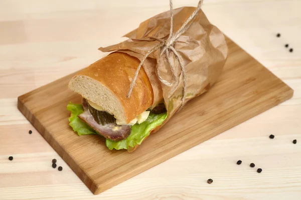 Grande baguette sub sandwich con prosciutto sul tagliere di legno — Foto Stock