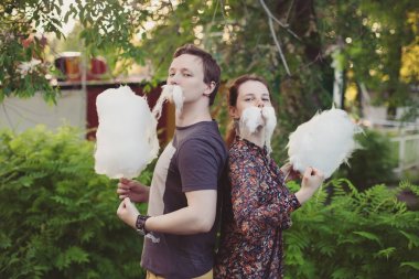 Happy loving couple with cotton candy having fun in park clipart