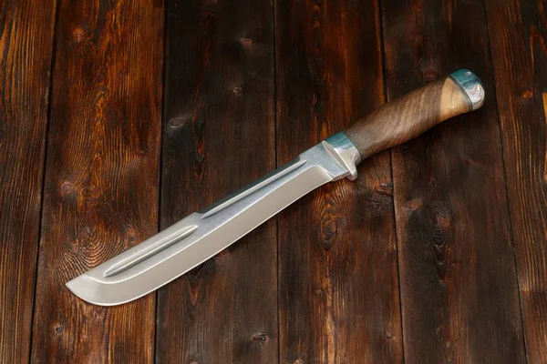 Grande faca de aço caça artesanal em um fundo de madeira, close-up — Fotografia de Stock