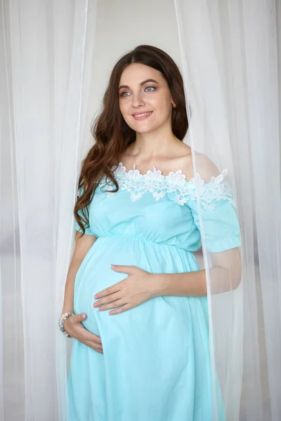 Mujer embarazada joven cerca de la cama en el estudio —  Fotos de Stock