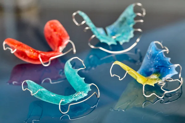 Frenos dentales coloridos o retenedores para dientes sobre fondo de vidrio — Foto de Stock